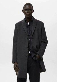 Abrigo de lana gris oscuro con cuello con solapas, diseño de un solo pecho y tres botones, combinado con una camisa y pantalones negros.