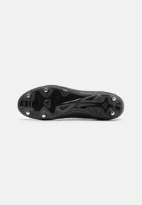 Suola di scarpette da calcio nera con gomma texturizzata, tacchetti posizionati strategicamente per la trazione e un design elegante e aerodinamico.