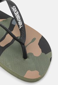 Infradito in gomma nera con plantare a motivo camouflage nei colori verde, marrone e nero. Presenta suola testurizzata e logo Havianas sulla cinghia.