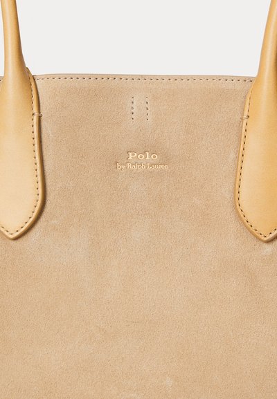 Borsa tote in suede beige con manici in pelle liscia, branding sottile e dettagli cuciti, con una finitura morbida e testurizzata.