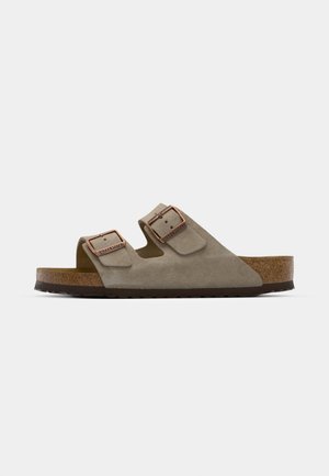 Infradito in suede grigio chiaro con due fibbie regolabili, un sottopiede in sughero e una suola in gomma strutturata.
