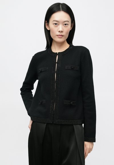 Μαύρο πλεκτό σακάκι με στρογγυλή λαιμόκοψη, διακοσμητικές χάντρες μπροστά και δύο τσέπες με διακοσμητικά κουμπιά. Λείο ύφασμα, εφαρμοστή γραμμή.