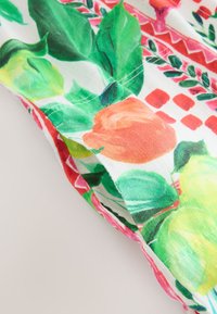 Blommigt bomullstyg med stora orange rosor och gröna blad mot en vit bakgrund, med rosa inslag och geometriska mönster.