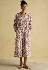 Baumwollkleid mit Blumenmuster, V-Ausschnitt, langen Ärmeln und gerafftem Bund. Präsentiert rote und grüne Blumen auf einem weißen Hintergrund.