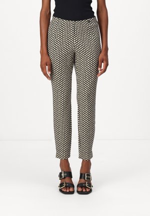 Zwart en crèmekleurige broek met een patroon en een tapered fit, voorzien van een gladde textuur en een elastische tailleband. Gecombineerd met zwarte sandalen.