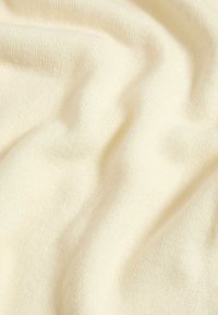 Jasnożółty materiał o gładkiej fakturze, ukazujący delikatne fałdy i drapowania, wykonany z nieokreślonego tworzywa, sugerujący ciepło i komfort.