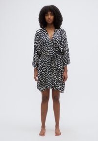 Μαύρο φόρεμα με λευκές πουά, μήκος έως το γόνατο, ελαφρύ ύφασμα, ζωνάκι στη μέση και φαρδιά μανίκια. Λεία υφή με φαρδιά εφαρμογή.