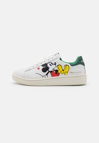 Vita låga sneakers med Mickey Mouse-grafik, grön texturerad hälflik och vita snören på en texturerad beige sula, sidovy.
