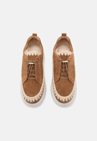 Chaussures en suede marron avec semelles en caoutchouc blanches, dotées d'un laçage à l'avant, de détails cousus et d'une doublure intérieure douce.