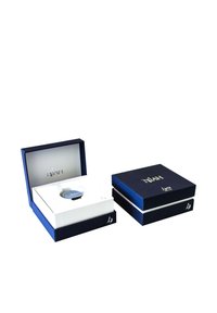 Confezione blu navy con accenti dorati. Un orologio è esposto in un inserto bianco, all'interno di una scatola aperta, con una seconda scatola accanto.