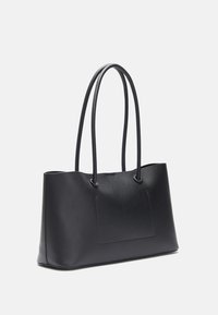 Musta nahkainen kassi, jossa on kaksi pitkää kantohihnaa, minimalistinen muotoilu, suorakulmainen muoto, sileä pinta ja hillitty etupaneelin yksityiskohta.