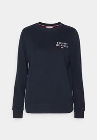 Marinblå sweatshirt i bomull. Har långa ärmar, ribbade muddar och rundad halsringning. Innehåller vitt "TOMMY HILFIGER"-logotyp på bröstet.