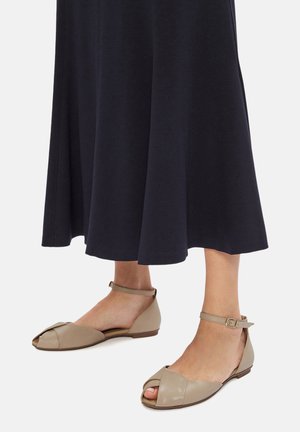 Bailarinas de cuero beige con diseño de punta abierta, que cuentan con una tira en el tobillo y una textura suave, combinadas con una falda fluida color marino.