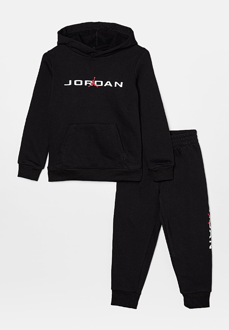 Ensemble de survêtement noir en deux pièces comprenant un sweat à capuche avec le logo "JORDAN" en blanc et rouge, et un pantalon assorti avec des poches latérales.