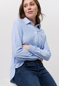 Lichtblauw-wit gestreept overhemd met knopen, een kraag, een losse pasvorm en knoopmanchetten, gecombineerd met donkere denim jeans.