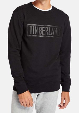 Felpa nera con colletto a girocollo, caratterizzata da un logo nero in rilievo "TIMBERLAND" sul davanti. Il tessuto sembra morbido con polsini a costine.