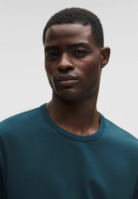 Dveškrátka z tehlového materiálu s krátkym rukávom a okrúhlym výstrihom, vyrobená z hladkej tkaniny, s čistým dizajnom a minimálnym počtom švov.