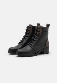 Bottines en cuir noir avec une tige en cuir texturé marron, lacets à l'avant, fermeture éclair sur le côté et semelle en caoutchouc épaisse. Design élégant et robuste.