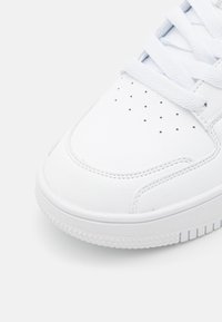 Sneaker bianca realizzata in pelle testurizzata, con punta liscia, perforazioni per la ventilazione e lacci piatti. Suola in gomma spessa con battistrada lineare.