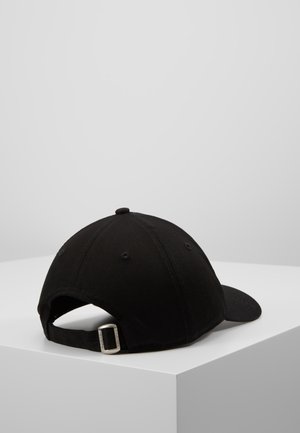 Sort justerbar baseballkasket med metal spænde placeret på en hvid piedestal mod en ensfarvet lysegrå baggrund.