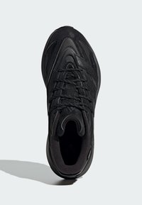 Čierna športová obuv s textúrovaným materiálom, viazaním a polstrovaným golierom. Má elegantný tvar a nenápadné logo na stranách.