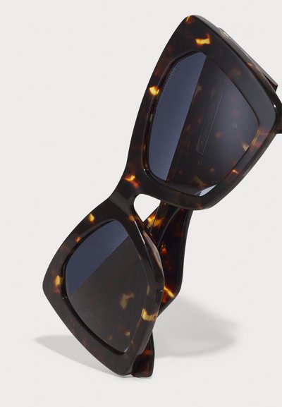 Schildpatt-Sonnenbrille mit übergroßem geometrischem Rahmen, dunklen Gläsern und glänzender Oberfläche. Verfügt über ein kantiges Design und eine leichte Konstruktion.