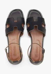 Zwarte leren sandalen met twee uitsnijdingen in de bovenste banden, open teen en een enkelbandje. Beige binnenzool met een geperst merklogo. Vierkante teenvorm.