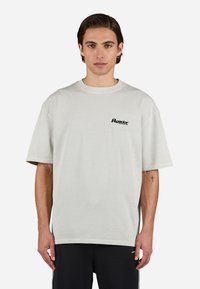 Light gray cotton t-shirt with short sleeves, rounded neck, and black logo on the left chest. Features a relaxed fit and straight hem.