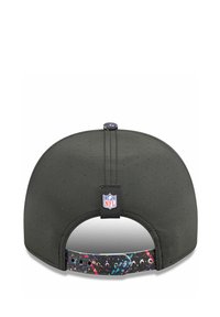 Casquette noire avec une surface texturée, présentant un design perforé. La sangle arbore un motif de taches de peinture multicolores. Étiquette avec le logo de la NFL accrochée.