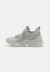 Sportowe sneakersy z siateczkowym wierzchem, ozdobione srebrnymi ćwiekami, jasnoszarymi akcentami oraz masywną, przezroczystą podeszwą. Sznurowadła i detal logo po boku.