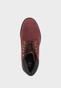 Burgunderfarbene Leder-Stiefeletten mit schwarzen Akzenten, runder Zehenpartie, goldenen Ösen, schwarzen Schnürsenkeln und einem gepolsterten Kragen für zusätzlichen Komfort.