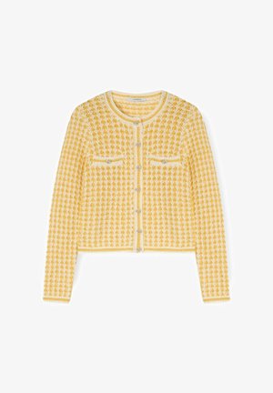 Cardigan tricoté texturé jaune et blanc avec manches longues, col rond, fermeture à boutons sur le devant et deux poches poitrine à boutons.