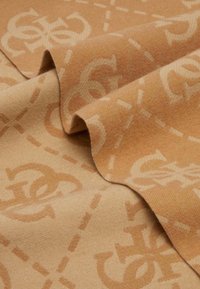 Tessuto beige con una texture morbida, caratterizzato da un sottile motivo di lettere intrecciate e linee tratteggiate in una tonalità leggermente più chiara.