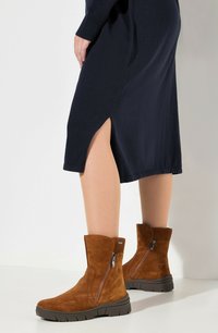 Ruske nubuk ankle boots med høy skaft, glidelås på siden og teksturert gummisåle, parret med en marineblå kjole med en sideslitt.