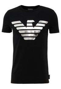 Svart bomullströja med en stor silverfärgad metallisk örnlogotyp på framsidan, korta ärmar och rundad hals.