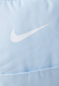 Lichtblauwe Nike-stof met een prominent wit logo. Het materiaal is gestructureerd met een subtiel weefpatroon, wat de grip en duurzaamheid verhoogt.