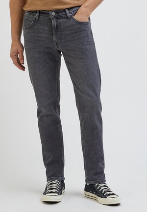 Jeans in denim grigio con una vestibilità dritta e delicate sfumature. Presentano tasche frontali, chiusura con zip e dettagli in rivetti. Abbinati a sneakers nere.