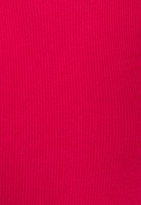 Primer plano de una textura de tela de color rosa brillante con líneas de punto verticales.