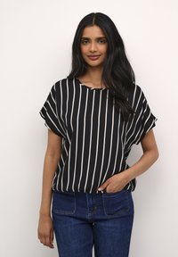 Blusa a righe bianche e nere con maniche corte e scollatura tonda, abbinata a jeans in denim blu. Tessuto morbido con una vestibilità comoda.