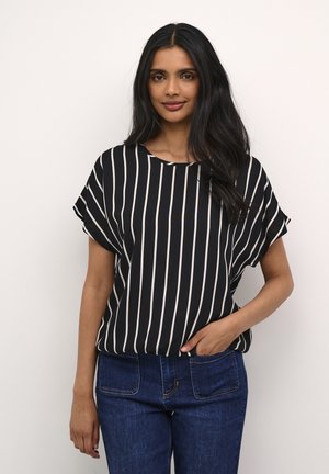 Blouse à rayures noires et blanches avec des manches courtes et un col rond, associée à un jean en denim bleu. Tissu doux avec une coupe décontractée.