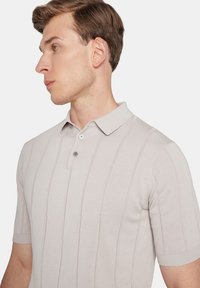 Jasnoszara koszulka polo z krótkim rękawem, z teksturowanym pionowym wzorem w paski, dwu guzikowym zapięciem oraz ribbowanym kołnierzykiem i mankietami.