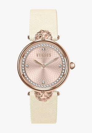 Rose gold watch with a textured light cream strap, round face with crystal accents, a patterned dial, and a lion detail on the strap's hardware.