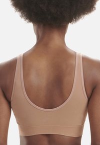 Podprsenka v jemné béžové látce, s kulatým výstřihem, tenkými ramínky a širokým žebrovaným páskem, navržená pro pohodlí a podporu.