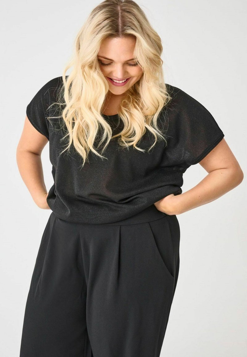 Haut noir à manches courtes avec une coupe décontractée et une texture douce, associé à un pantalon plissé noir. Design simple et élégant sans embellissements.