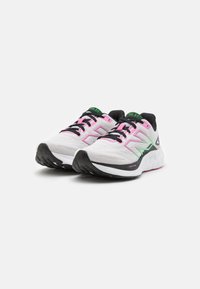 White athletic shoes with pink and green accents, textured fabric upper, black laces, and cushioned sole featuring a patterned tread.