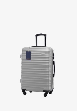 Stříbrný tvrdý kufr s žebrovanou texturou, teleskopickou rukojetí a čtyřmi kolečky. Obsahuje přívěsek s logem pro identifikaci.