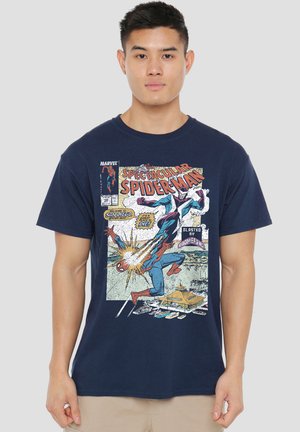 Young man wearing a navy blue T-shirt with a colorful vintage comic-style Spiderman graphic and text on front.