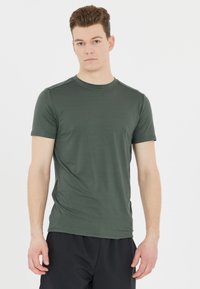 Grön kortärmad t-shirt i slätt tyg med rund halsringning och minimalistisk design. Bärs med svarta träningsshorts.