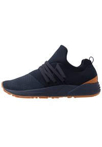 Baskets de sport navy avec tige perforée, détails de sangle élastique, accents beige et semelle en caoutchouc. Design élégant et profil bas pour le confort.