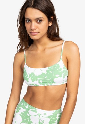 Haut de bikini floral vert et blanc avec de fines bretelles, un décolleté carré et une coupe ajustée. Le motif présente de grandes feuilles de monstera.